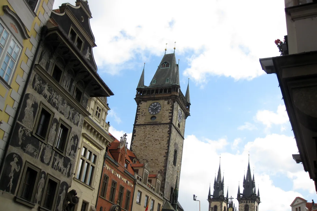 緑の尖塔と時計の文字盤を備えたOld Town Hall Towerを、路地から望む一枚。背後にはTýn Churchが控えています。